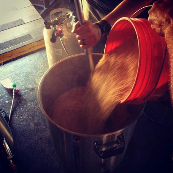 Alexandria Brewing Company Beer Making hops being poured out of a bucket during Alexandria Brewing Company's beer making process