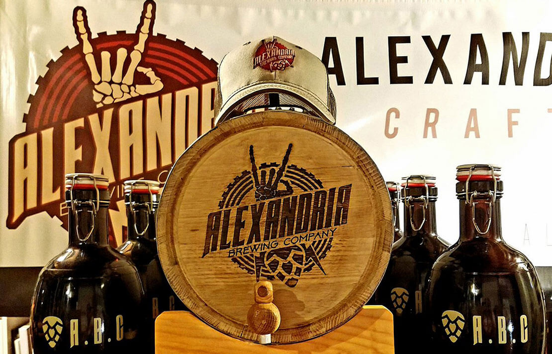 Alexandria Brewing Company Swag Alexandria Brewing Company's logo and alternate marks are showcased on a banner, hat, growlers, and barrel