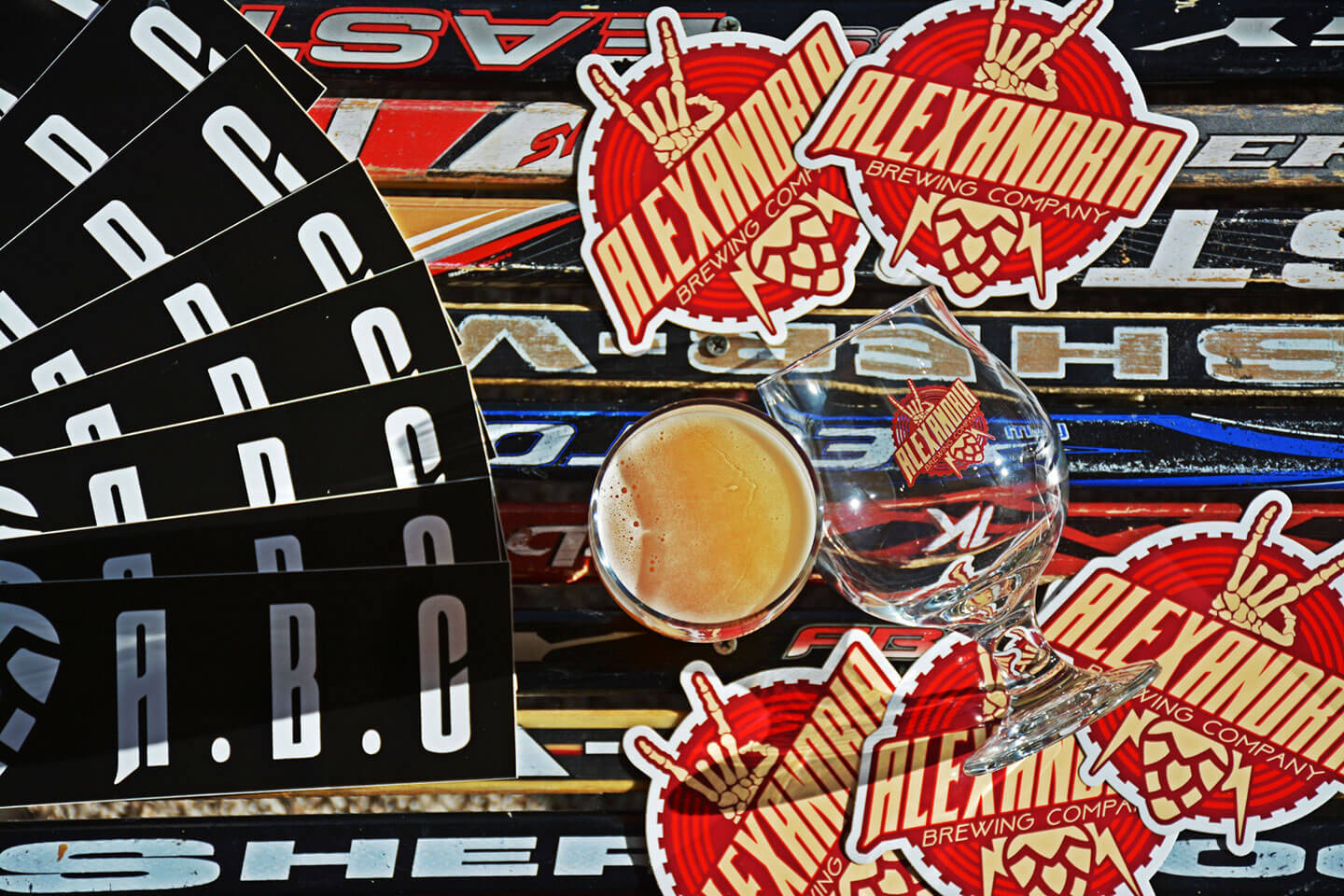 Alexandria Brewing Company Stickers Several stickers featuring the Alexandria Brewing Company logo and alternate mark are displayed on a table